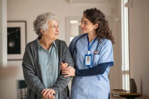 Young caregiver helps senior woman to walk